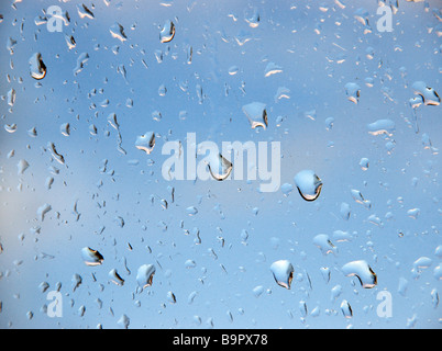 Rain drops on a window pane, looking out to a brightening sky. Stock Photo