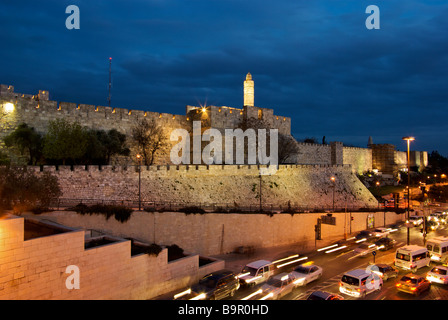 Illuminated Tower of David and minaret near Jaffa gate into old walled city Jerusalem in early evening with rush hour traffic Stock Photo