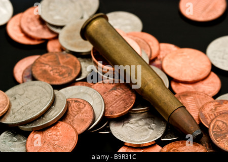 Large caliber bullet in a pile of American coins Stock Photo