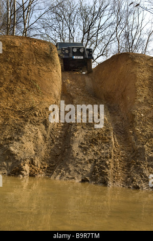 A Land Rover Defender 90 about to descend a steep hill into a river on an offroad driving track in Sussex UK. Stock Photo