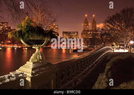 View of Central Park West the Lake and Bow Bridge from Bow Bridge in Central Park New York City at dusk Stock Photo