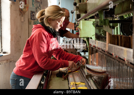 A young woman setting up yarns on the the weaving loom at Melin Tregwynt welsh woollen mill Castlemorris Pembrokeshire wales UK Stock Photo