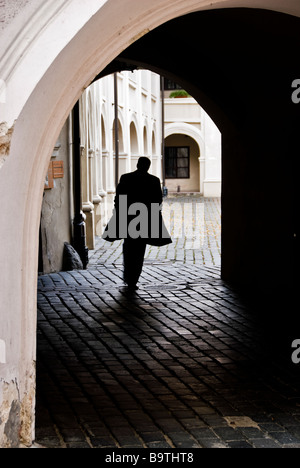 Silhouette of a man walking away in a narrow cobbled street, Vilnius old town, Lithuania, Europe Stock Photo