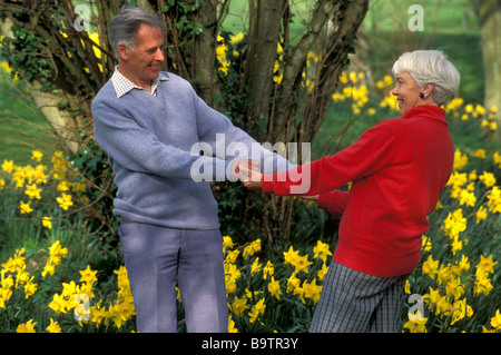 Happy mature couple holding hands surrounded by daffodils Stock Photo