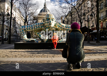 Woman taking a picture of her daughter by a colourful statue of a man in front of the Sorbonne University, Paris, France, Europe Stock Photo