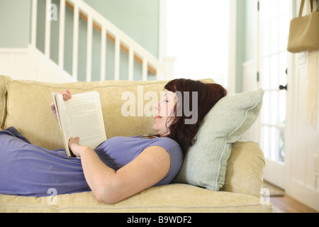 Woman on sofa reading book Stock Photo