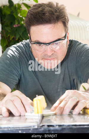 Worker using table saw and water to cut ceramic tiles  Stock Photo