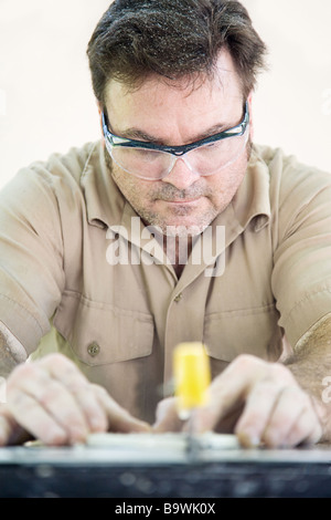 Tile setter using a table saw to cut ceramic tile  Stock Photo