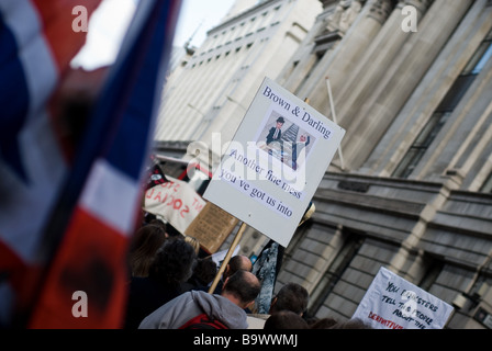 A protest placard stating 'Brown & Darling another fine mess you've got us into' is held above the crowd at the G20 protests. Stock Photo