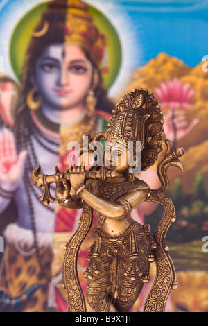 Brass Statue of Indian (Hindu) God Krishna playing the Flute with colourful Indian background Stock Photo