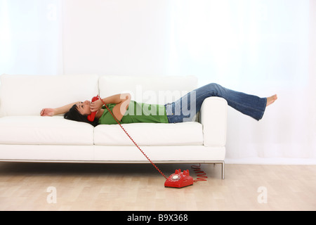 Woman laying on couch talking on retro telephone Stock Photo