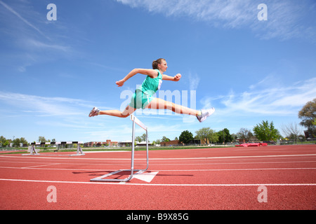 Woman jumping over hurdle Stock Photo