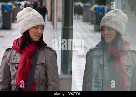 Young Vietnamese American Woman Looking at her Reflection in a Window in Cordoba Spain Stock Photo