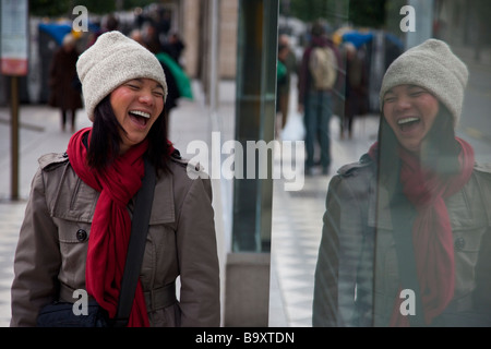 Young Vietnamese American Woman Looking at her Reflection in a Window in Cordoba Spain Stock Photo