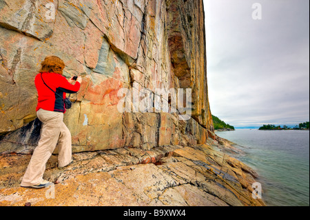 Tourist viewing the ancient pictographs on Agawa Rock, Agawa Rock Pictographs Trail, Lake Superior, Lake Superior Provincial P. Stock Photo