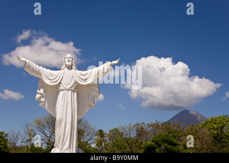 Statue of Jesus at the Cementerio Los Angeles in Moyogalpa, Nicaragua on Ometepe Island with the Volcan Concepcion looming behind. Stock Photo