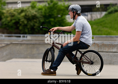 Young Man Wearing Helmet Sitting on a BMX Bike at the Louisville Extreme Skate Park in Louisville Kentucky Stock Photo