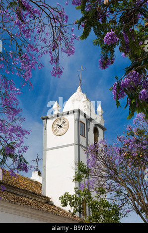 Portugal the Algarve, Moncarapacho church clock tower, jacaranda tree in flower Stock Photo