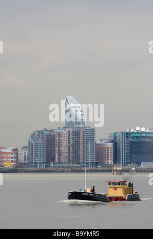 Working boat on River Thames London UK.  Residential development at New Providence Quay including Ontario Tower in background. Stock Photo