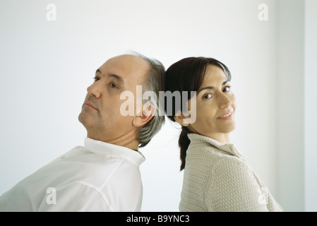 Mature couple standing back to back, leaning backwards, touching heads Stock Photo