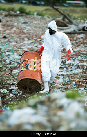 Person in protective suit carrying barrel of hazardous waste Stock Photo