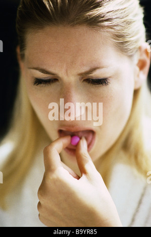 Woman placing pill on tongue Stock Photo
