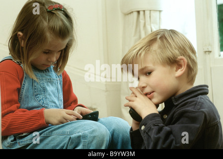 Children using phones, boy covering mouthpiece Stock Photo