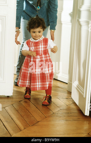 Little girl walking, mother following behind Stock Photo