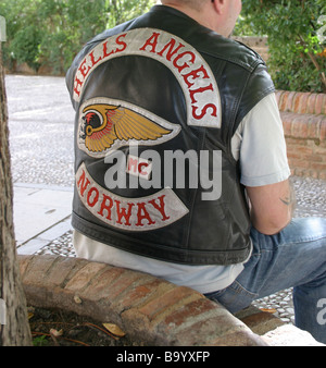 Hells Angels Norway. A man in a  short sleved leather biker jacket sits on a brick planter in the historic Spanish palace. Stock Photo