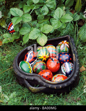 Hand painted decorative easter eggs in heart-shaped container ready to be hidden in the garden. Stock Photo