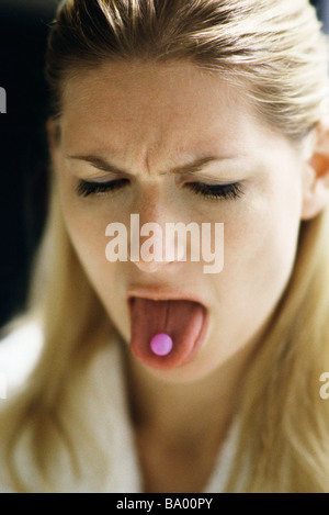Woman sticking out tongue, showing pill Stock Photo