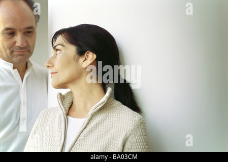 Mature woman leaning against wall looking at husband Stock Photo