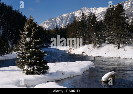 Wading fishermen on Madison River in winter with snow covered Rocky mountain Madison Range Montana Stock Photo
