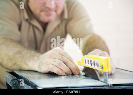 Closeup of a tile worker s hands as he cuts ceramic tile with a table saw  Stock Photo