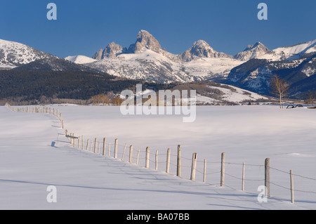 Mount Owen Grand Teton Middle Teton and South Teton in winter from Idaho with fence in snow covered field Stock Photo