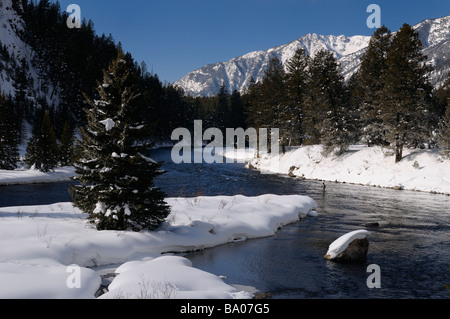 Men Wading on Madison River in winter fly fishing with snowy Rocky mountain Madison Range Montana Stock Photo