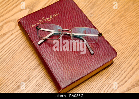 A pair of reading glasses resting on a book of Longfellow poems.