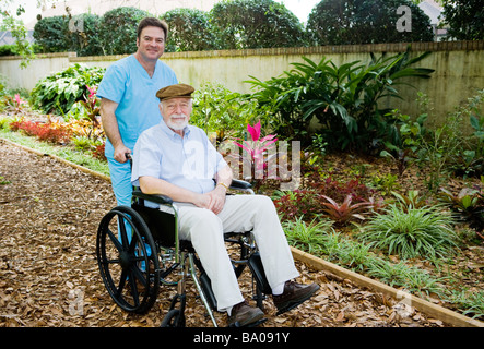 Nursing home orderly takes a senior man for a walk in the garden  Stock Photo