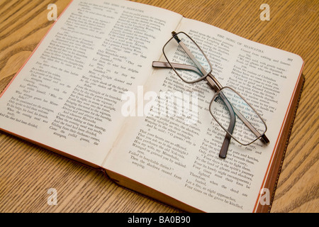 A pair of reading glasses resting on a book of Longfellow poems.