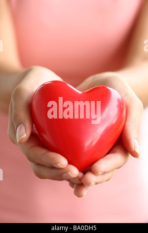 Human hand holding a red heart with a Christian cross isolated over ...