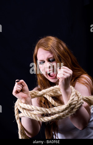 Young woman being tied up wit ha rope Stock Photo