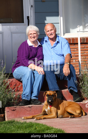 Senior couple with dog sitting on porch Stock Photo