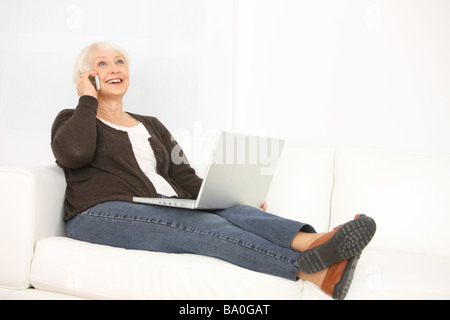 Senior woman with laptop talking on cell phone Stock Photo