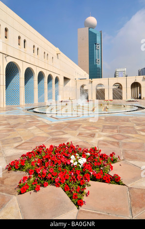 Abu Dhabi Cultural Foundation paved courtyard and fountain with red petunia flowers Stock Photo