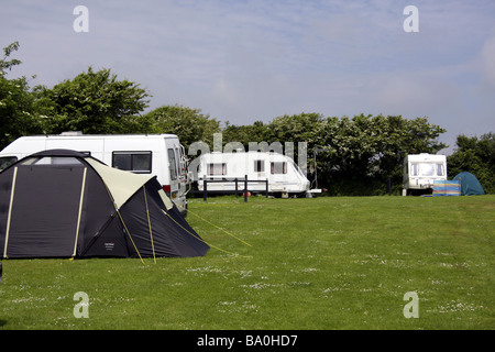 Caravans and a tent in a sunlit field at a holiday site near Port Eynon, Gower Peninsular, South Wales Stock Photo