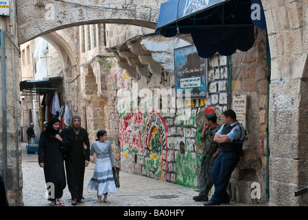 Israel. Jerusalem Old City. Muslem Quarter. 3 palestinian women walking passed 2 israeli policemen Stock Photo