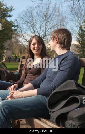 Young couple talk and relax in a public park in England, UK Stock Photo