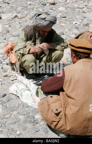 Afghan men wearing traditional hat and turban, market near Ishkashim on the border between Tajikistan and Afghanistan Stock Photo