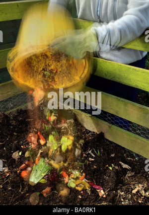 Bucket of kitchen waste being poured into a compost heap. Stock Photo