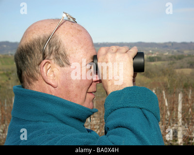 Man looking for something through binoculars in the countryside Stock Photo